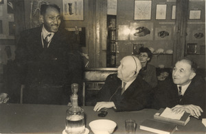 Unidentified man speaks while two other unidentified men look on