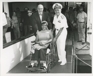 Woman in wheelchair assisted on ramp