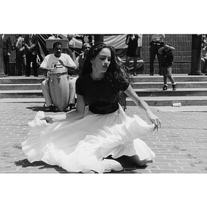 A woman kneels on the ground while dancing