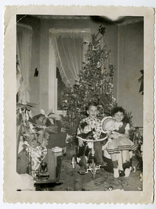 Children in front of Christmas tree, with gifts