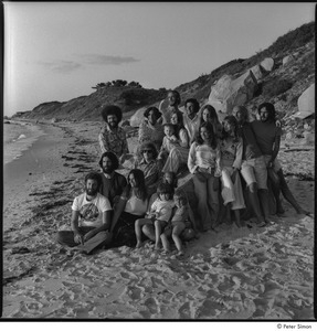 Ram Dass and Satsang: Ram Dass posing on the beach with a group including Ronni Simon at left, Tukaram Das at back center, Daniel Goleman at back left, and Mirabai Bush and Chaitanya Maha Prabu seated at front