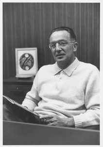 Edwin Rossman seated, holding publication