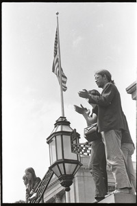 Demonstration at State House against the killings at Kent State: protesters applauding, American flag in background