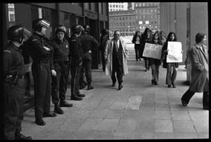 Small group of protesters file past police at the entrance to the John F. Kennedy Federal Building