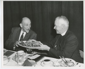 Unidentified men passing a plate Thanksgiving dinner