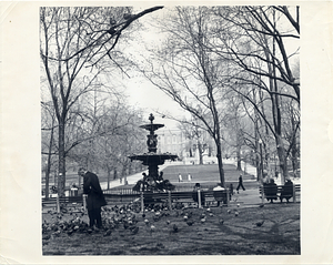 People sitting on benches in Boston Common facing Brewer Fountain with the Massachusetts State House in the background