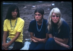 Three women seated on remnants of the grass, Woodstock Festival