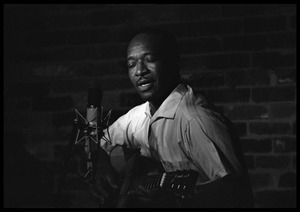 Josh White performing on guitar in a coffeehouse