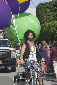 Parade marcher on tricycle, towing large helium balloons : Provincetown Carnival parade