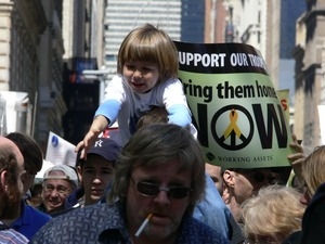 Child on her parent's shoulders, marching in the streets to oppose the war in Iraq