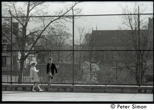 Young boy and girl on a playground, standing by a cyclone fence
