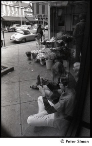 Young people seated in the entryway to a florist shop across the street from the Cafe Mediterraneum