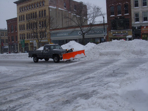 Truck plowing on Main Street, Northampton, Mass., near Gothic Street, amid deep piles of plowed snow
