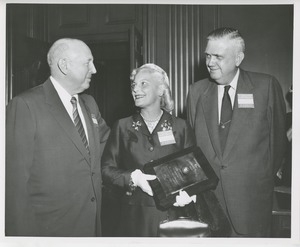 Margaret Milbank Bogert holds the 1956 President's Trophy and poses with two men