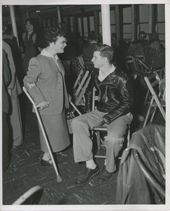 Young woman using crutches and young man talking