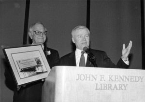 William Bulger speaking into microphone behind podium at "Irishman of the Year" event honoring Congressman John Joseph Moakley at John F. Kennedy Library