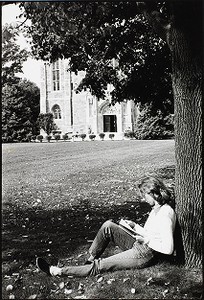 Student reading beneath a tree on the lawn of the Bapst Library at Boston College