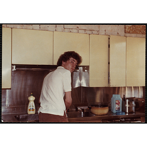 A male staff member, standing at a sink, turns his head