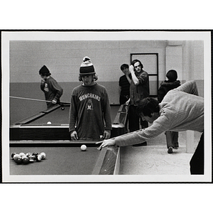 A male staff member playing pocket billiards while a boy looks on