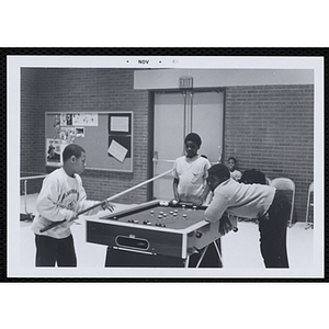 Three boys playing a game of bumper pool