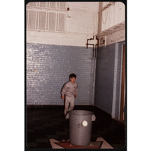 A boy stands behind a trash can at the Charlestown gymnasium