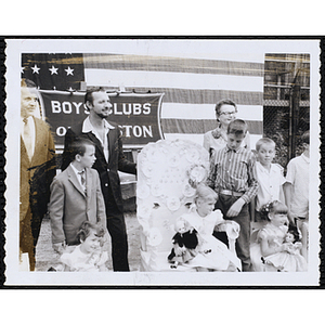 The Little Sister Contest winners sitting with dolls while their brothers and the panel of judges stand behind them