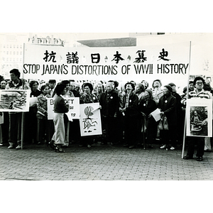 Chinese protesters at a demonstration holding up a banner that says, "Stop Japan's Distortions of WWII History"