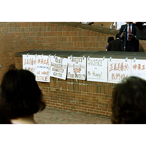 Protest signs taped to a brick wall at the rally for Long Guang Huang in City Hall Plaza in Boston