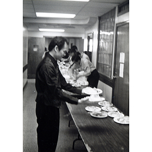 Man sets plates down next to the buffet table during a Thanksgiving celebration held at Association headquarters