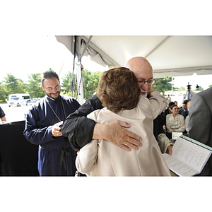 A woman hugs a Greek Orthodox priest at the groundbreaking ceremony for the George J. Kostas Research Institute for Homeland Security