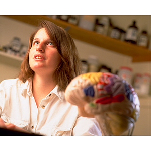 Nikki Boucher seated in a lab with a model of the human brain