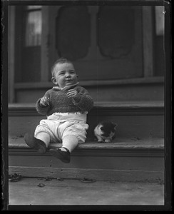 Toddler sitting on a stoop with a kitten