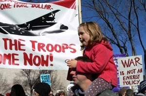 Protesters on the National Mall, one with a child on his shoulders, marching against the War in Iraq