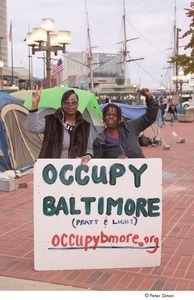 Occupy Baltimore: two women posing with raised fist and peace sign behind 'Occupy Baltimore' sign