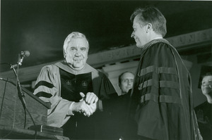 David C. Knapp shaking hand of unidentified man at podium