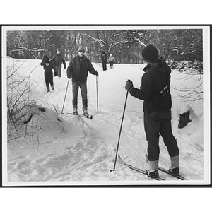 Adult facing group of cross country skiers in woods