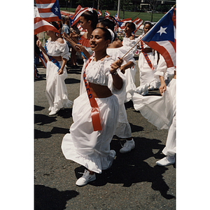 A girl wearing white waves a Puerto Rican flag during the Festival Puertorriqueño parade