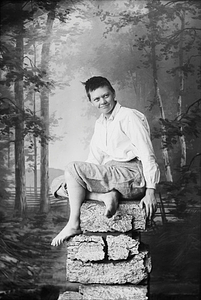 Marie Høeg Sits on a Pile of Rocks in Traditional Men's Attire