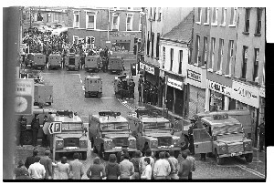 Two rows of RUC Land Rovers keeping warring factions, the Nationalists (near the camera) and Loyalists, apart on Irish Street, Downpatrick