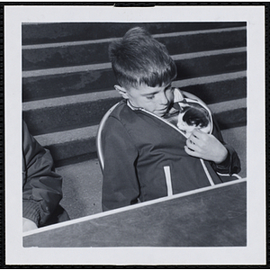 A boy sitting with his cat in his jacket in a Boys' Club Pet Show