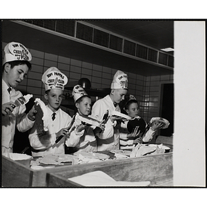 Members of the Tom Pappas Chefs' Club frost cakes in a kitchen