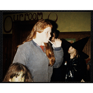 A girl chews on a straw at a Halloween party