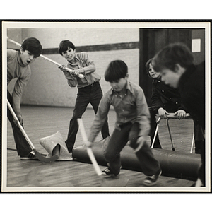 Boys play floor hockey in a gymnasium