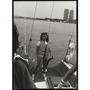 A girl holds a rudder as she stands on the deck of a sailboat in Boston Harbor