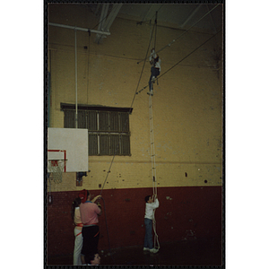 A child climbs a rope ladder in a gymnasium