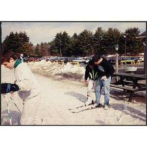 A man helps a boy put skis on at a resort