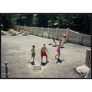 Three boys walk around a picnic area in Water Country water park during a Tri-Club field trip