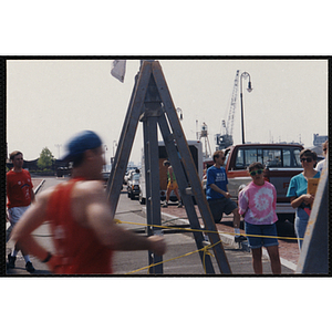 A man finishes the Bunker Hill Road Race as spectators look on