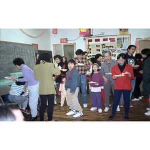 Guests hold plates of food at Chinese Progressive Association's celebration of the Chinese New Year