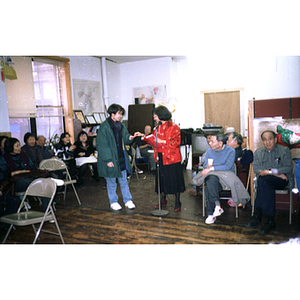 Suzanne Lee hands an award or gift to a young woman at the Chinese Progressive Association's celebration of the Chinese New Year